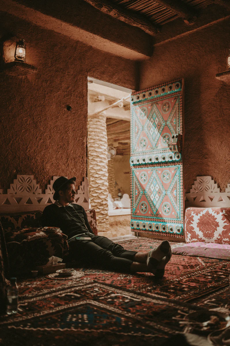 Paint By Numbers | Riyadh - Man In Black Jacket And Black Pants Sitting On White And Red Floral Couch